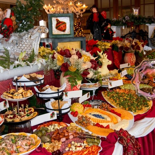 A festive Christmas buffet table laden with various appetizers, cheeses, meats, and desserts.