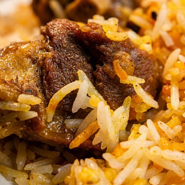 Close-up of flavorful biryani with tender meat pieces and spiced basmati rice.