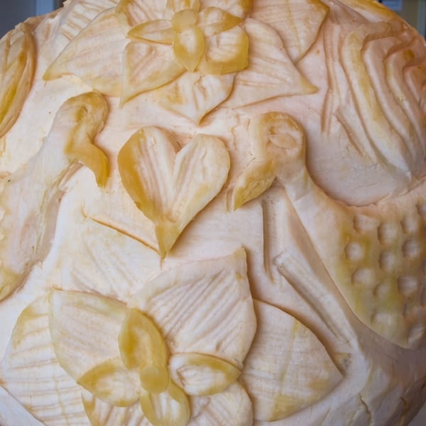 Intricately carved fruit or vegetable centerpiece featuring doves, hearts, and floral patterns.