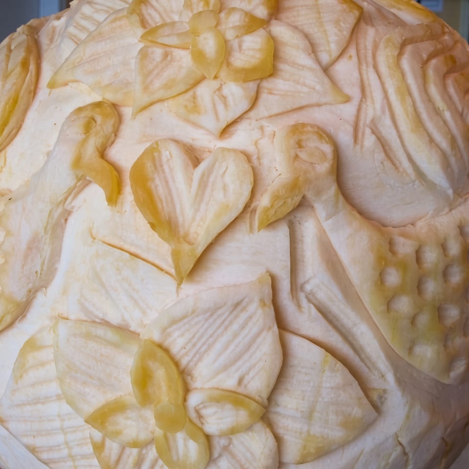 Intricately carved fruit or vegetable centerpiece featuring doves, hearts, and floral patterns.